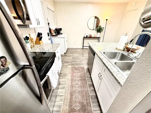 a kitchen with stainless steel appliances granite countertop a stove refrigerator a sink dishwasher and wooden cabinets with wooden floor