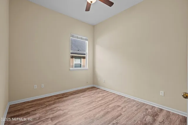 an empty room with a hardwood and ceiling fan