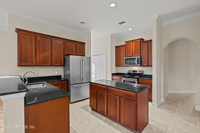 a kitchen with stainless steel appliances granite countertop a stove top oven a sink and dishwasher a refrigerator with wooden cabinets