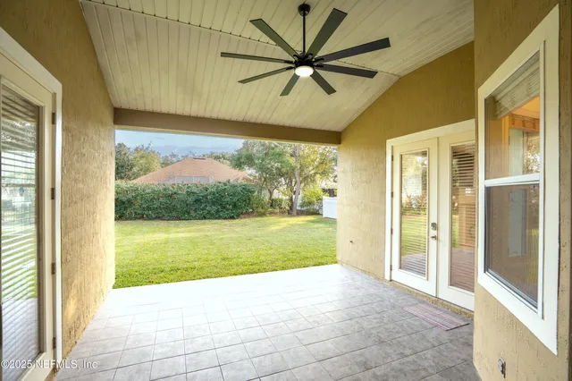 a view of a big room with wooden floor a ceiling fan and front door