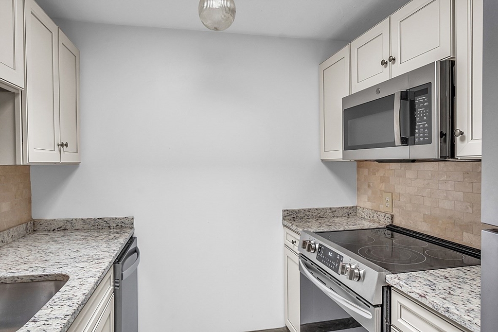 10 Mill Street, Unit B Maynard, MA 01754 - Photo 11 of 21 a kitchen with granite countertop a sink stove and cabinets