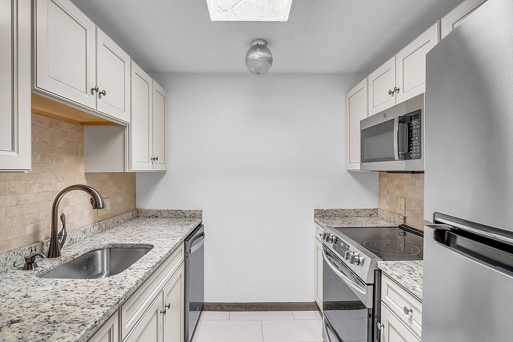 10 Mill Street, Unit B Maynard, MA 01754 - Photo 9 of 21 a kitchen with stainless steel appliances granite countertop a sink stove and microwave