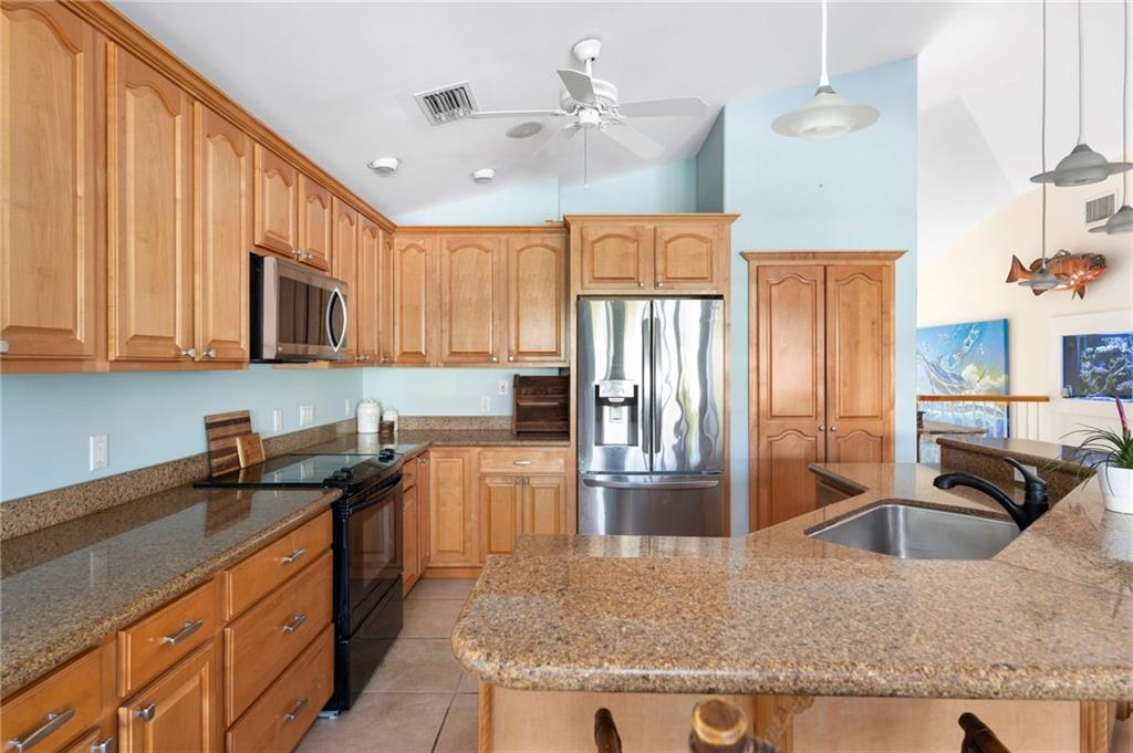 5440 95th Street Sebastian, FL 32958 - Photo 11 of 36 a kitchen with stainless steel appliances granite countertop a sink a stove and a refrigerator
