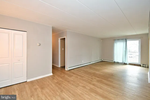 an empty room with wooden floor and windows