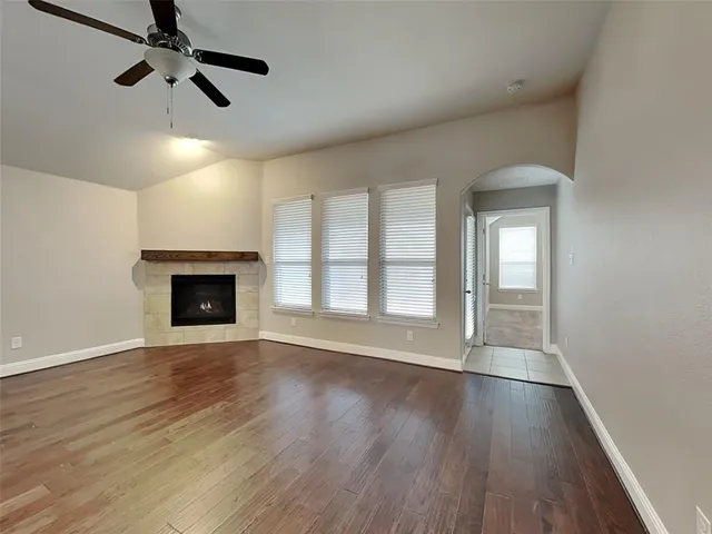 a view of an empty room with wooden floor fireplace and a window