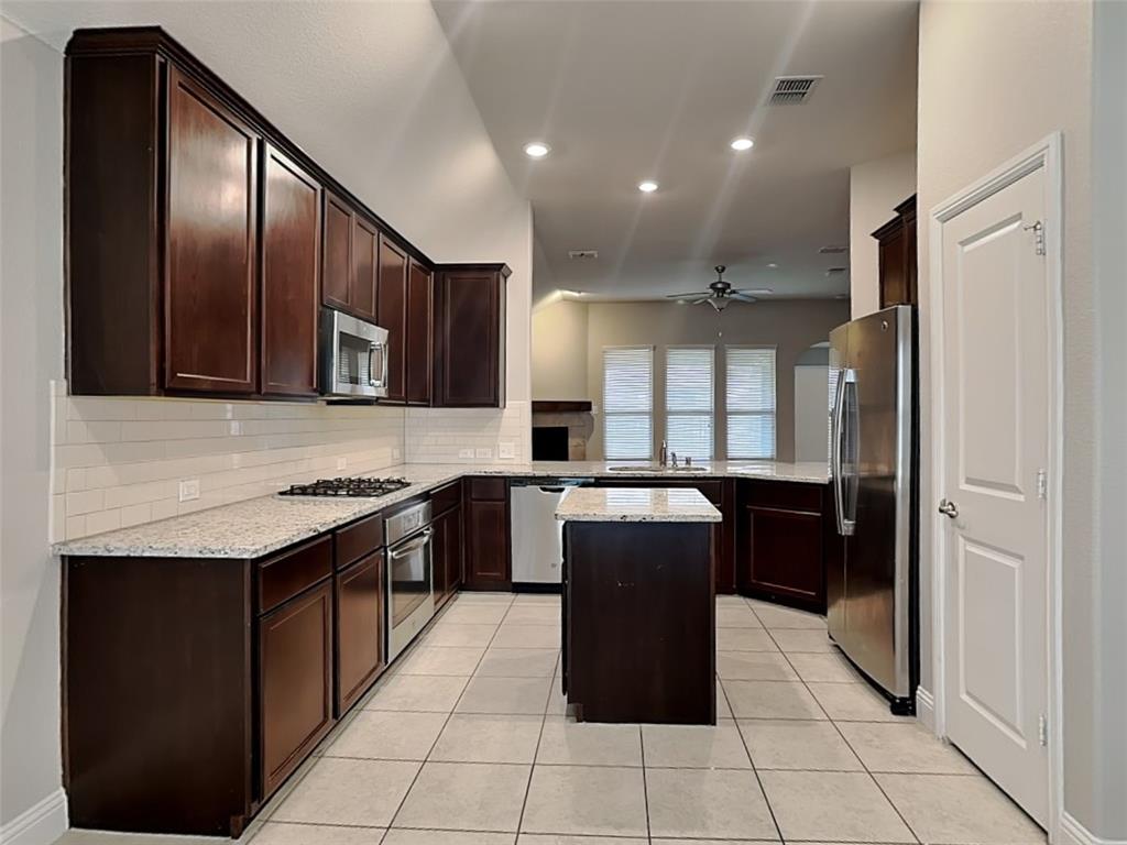7248 Laguna Del Campo Trail Fort Worth, TX 76131 - Photo 3 of 15 a kitchen with granite countertop stainless steel appliances a sink counter space cabinets and a window