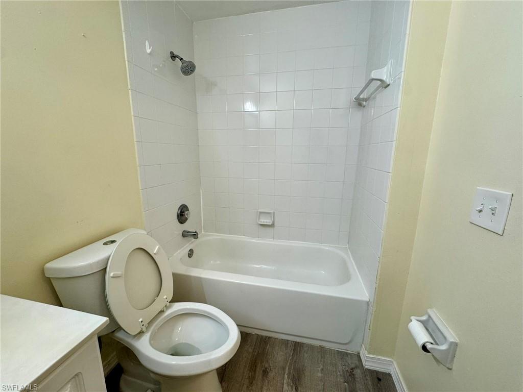 2153 Sunshine Boulevard, Unit 4 Naples, FL 34116 - Photo 15 of 19 Full bathroom featuring toilet, tiled shower / bath, vanity, and wood-type flooring