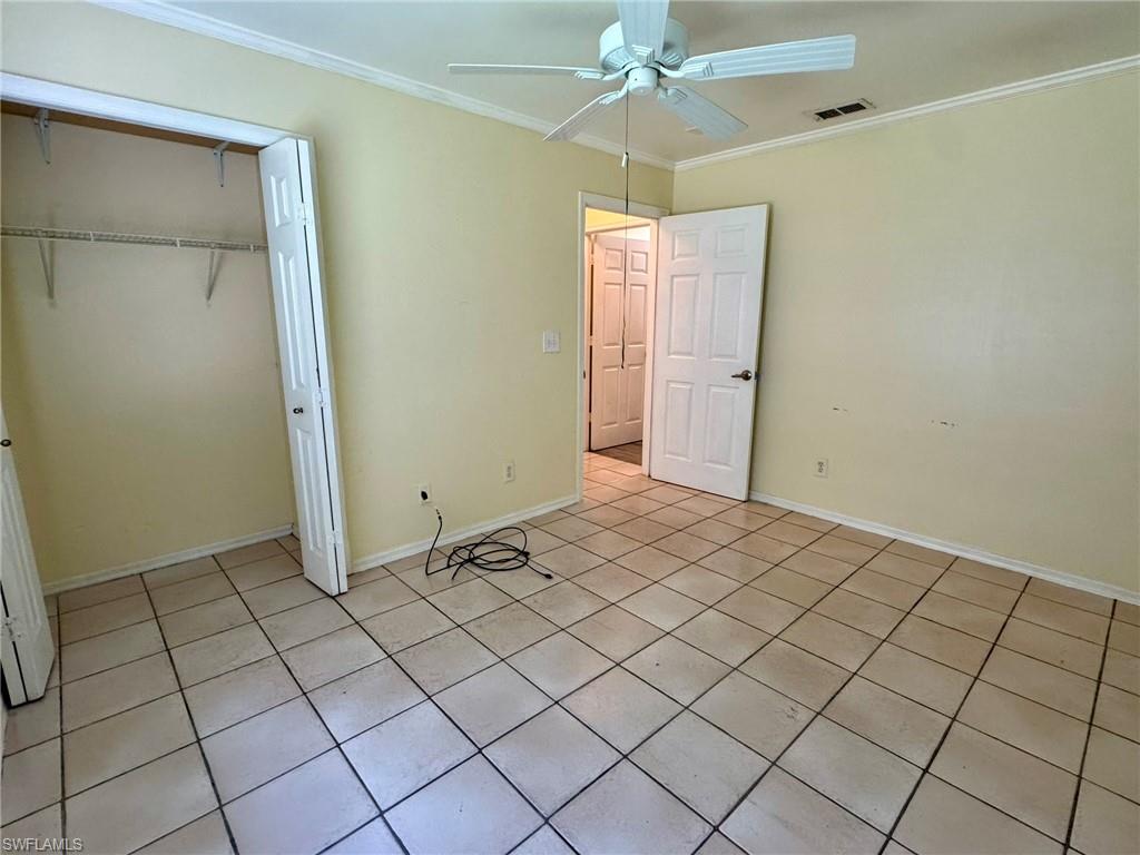 2153 Sunshine Boulevard, Unit 4 Naples, FL 34116 - Photo 17 of 19 Unfurnished bedroom featuring a closet, ornamental molding, light tile patterned floors, and ceiling fan