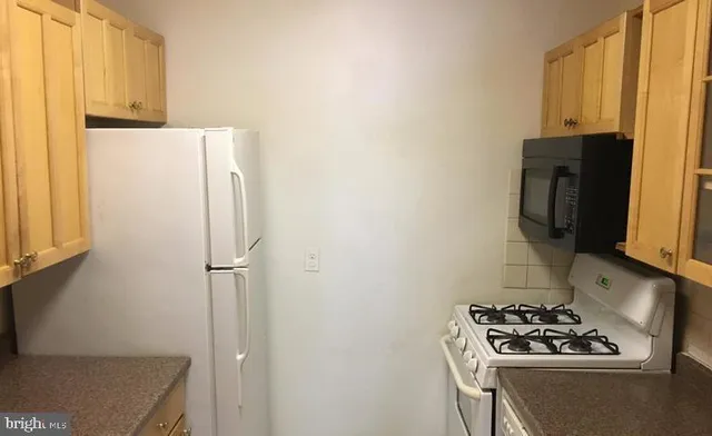 a white refrigerator freezer and a stove sitting inside of a kitchen