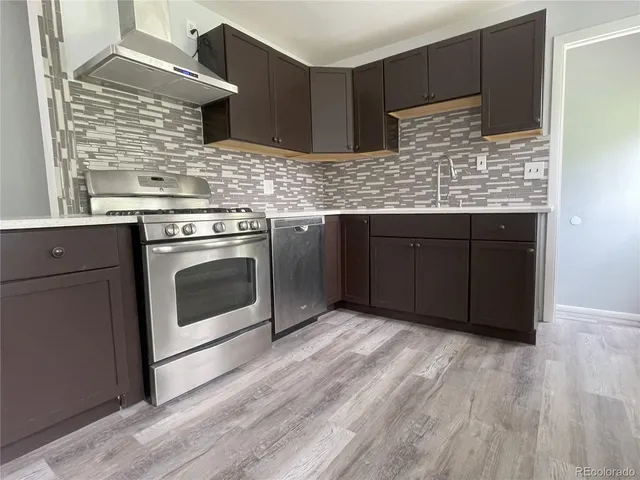 a kitchen with stainless steel appliances granite countertop wooden cabinets and a wooden floor