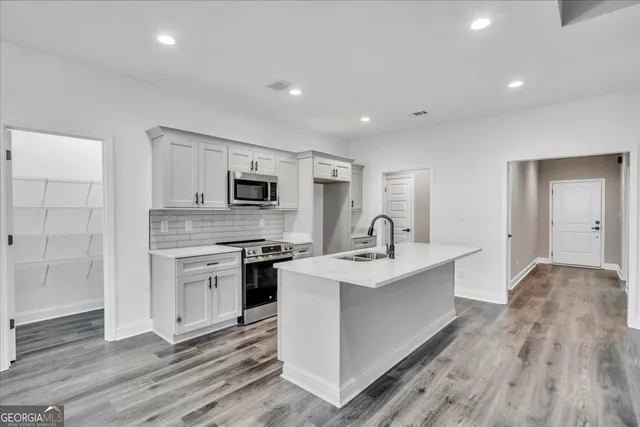 a view of a kitchen with sink stainless steel appliances and wooden floor