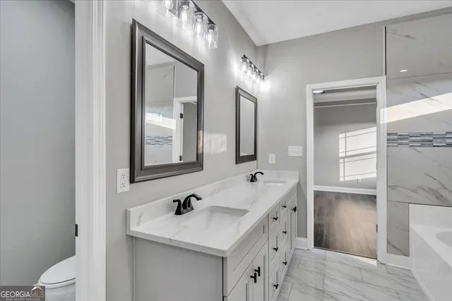 a bathroom with a sink a toilet a mirror and shower