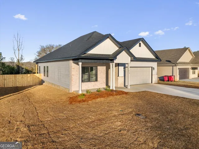 a front view of house with yard and trees in the background
