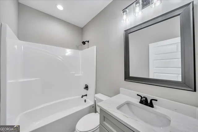 a bathroom with a bathtub shower sink vanity mirror and toilet
