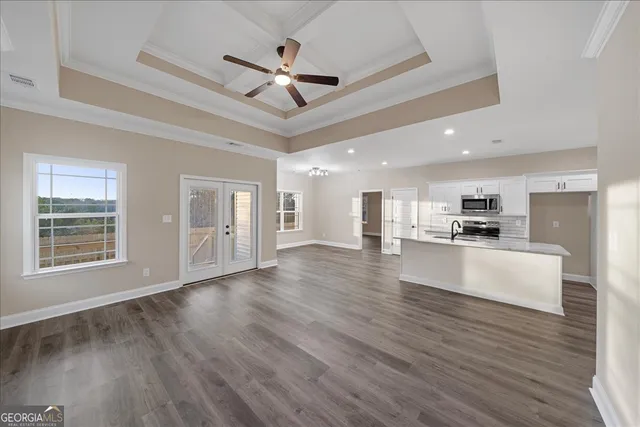 a view of an empty room with wooden floor and a ceiling fan