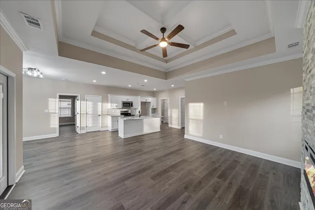 a view of an empty room with wooden floor and a ceiling fan