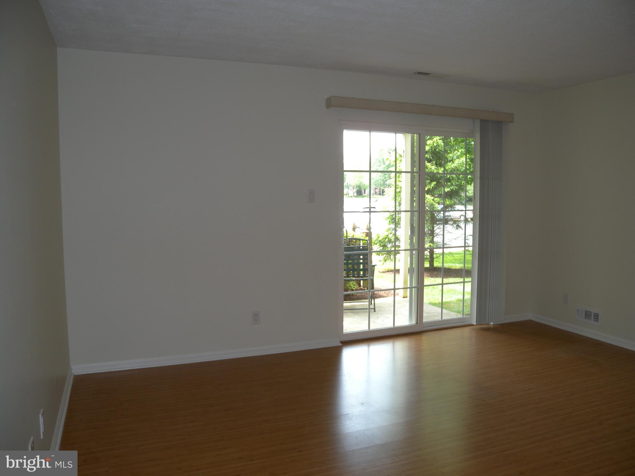 1907 A Sutton Place Mount Laurel, NJ 08054 - Photo 3 of 23 a view of an empty room with wooden floor and a window