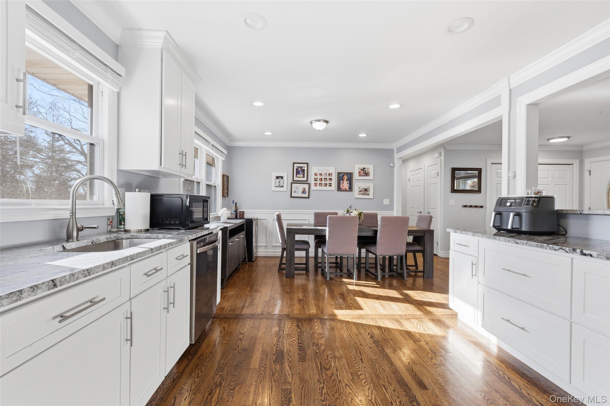 39 Benjamin Road Mahopac, NY 10541 - Photo 8 of 39 Kitchen with white cabinets, light stone counters, crown molding, dark wood-style flooring, and black microwave