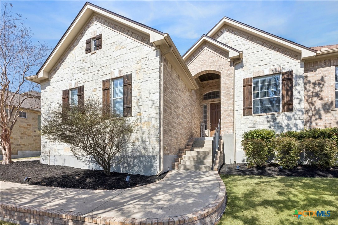 Stone and brick detailing accent the exterior as a staircase leads up to a covered front entry framed by classic architectural lines.
