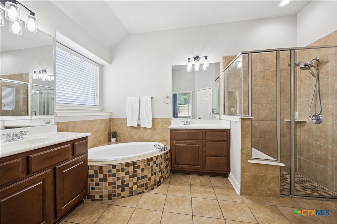 2309 First View Leander, TX 78641 - Photo 19 of 31 The primary bath offers a spa-like feel with dual vanities, a soaking tub, and a separate walk-in shower.