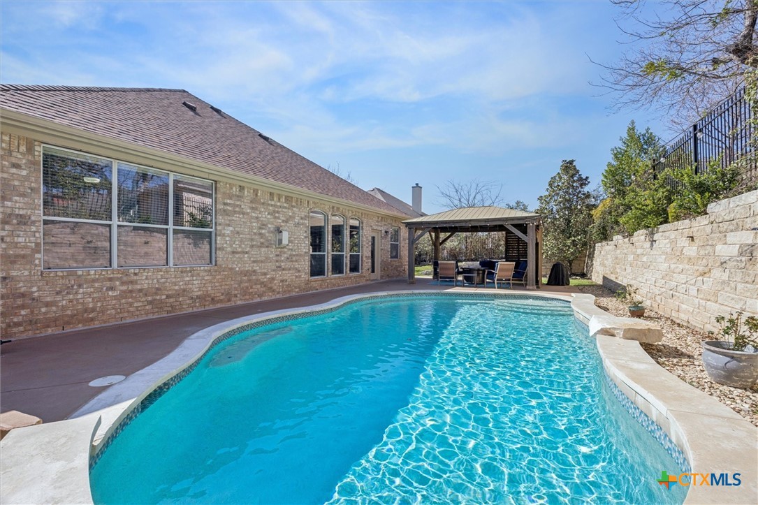 2309 First View Leander, TX 78641 - Photo 26 of 31 The backyard features a beautifully shaped pool alongside the rear exterior of the home, with multiple windows bringing natural light inside.