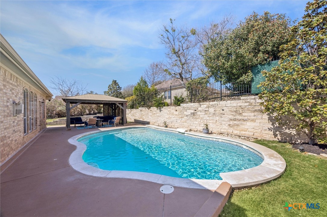 2309 First View Leander, TX 78641 - Photo 27 of 31 A sweeping view of the backyard showcases the inviting pool, stone retaining wall, and landscaped greenery that add both beauty and privacy.