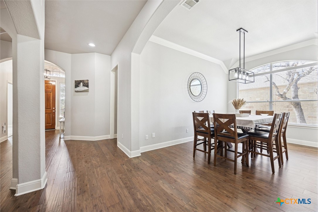 2309 First View Leander, TX 78641 - Photo 6 of 31 Warm wood-look tile flooring flows through an elegant dining space framed by graceful archways that connect seamlessly to the rest of the home.