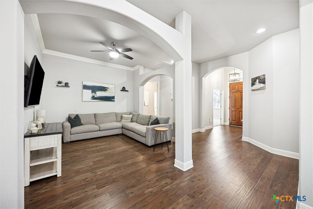 2309 First View Leander, TX 78641 - Photo 9 of 31 The living room showcases an open layout with rich flooring, architectural arches, and clear sightlines back toward the front entry.