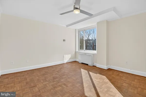 an empty room with chandelier fan and windows