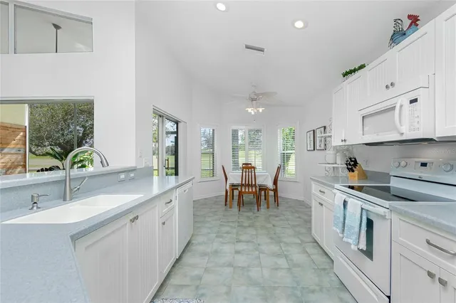 a large white kitchen with stainless steel appliances granite countertop lots of white cabinets a stove and a sink