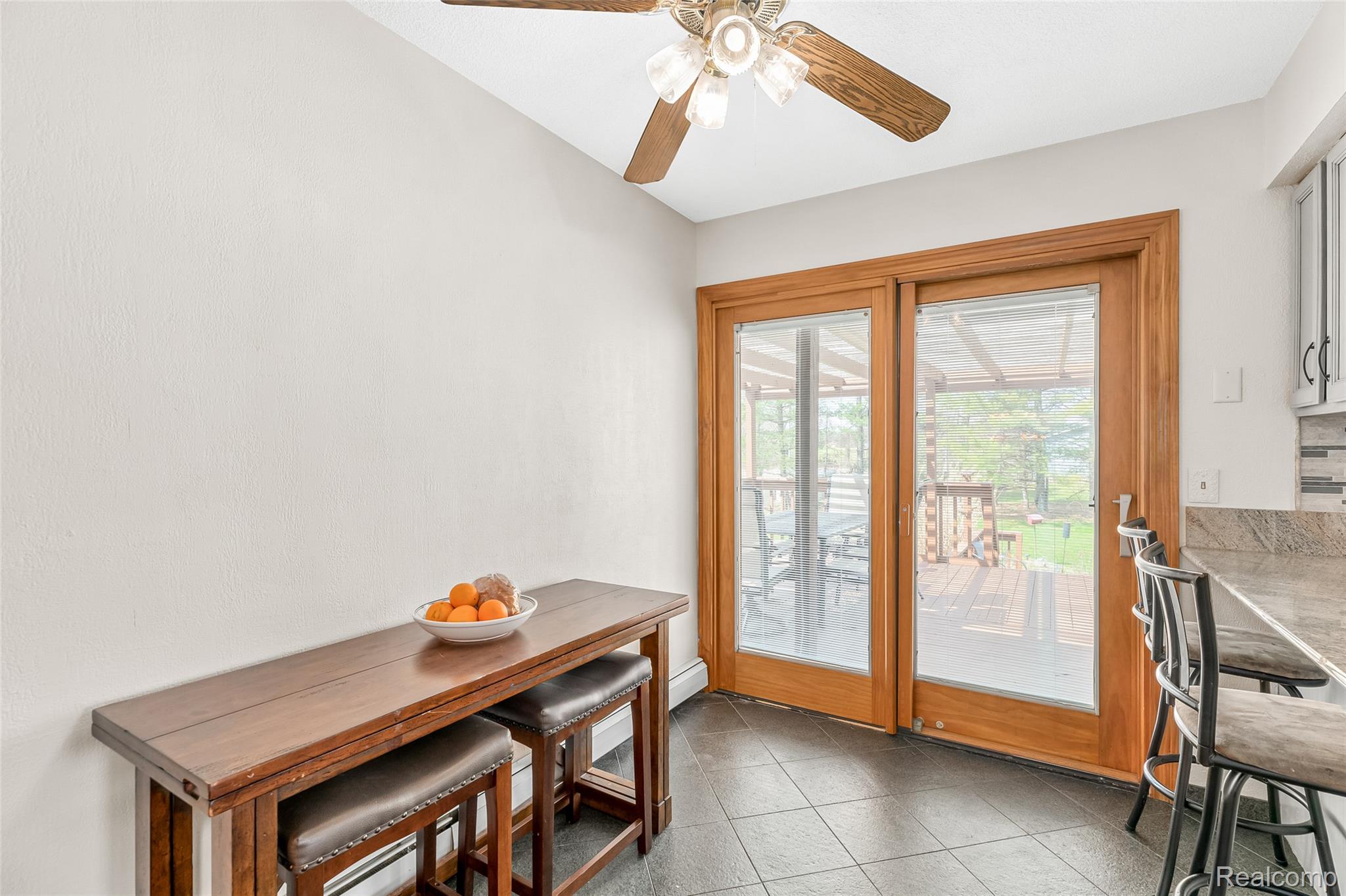 15395 Osius Road Chelsea, MI 48118 - Photo 12 of 55 Sliding glass patio doors providing outdoor access, ceramic tile flooring, ceiling fan with wood-finish blades, and a textured backsplash