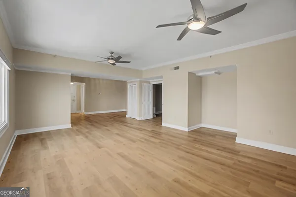 a view of empty room with wooden floor and fan