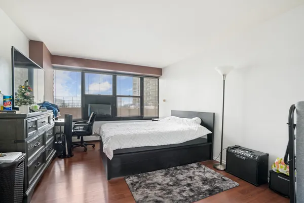 a bedroom with a bed a dresser next to a window