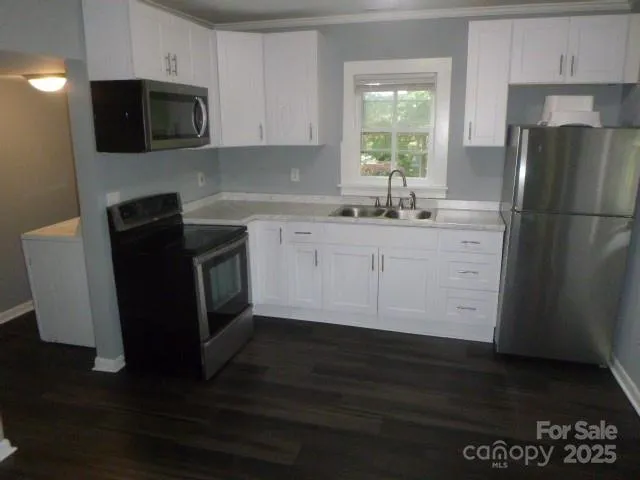 a kitchen with granite countertop a refrigerator a stove a microwave and wooden floor