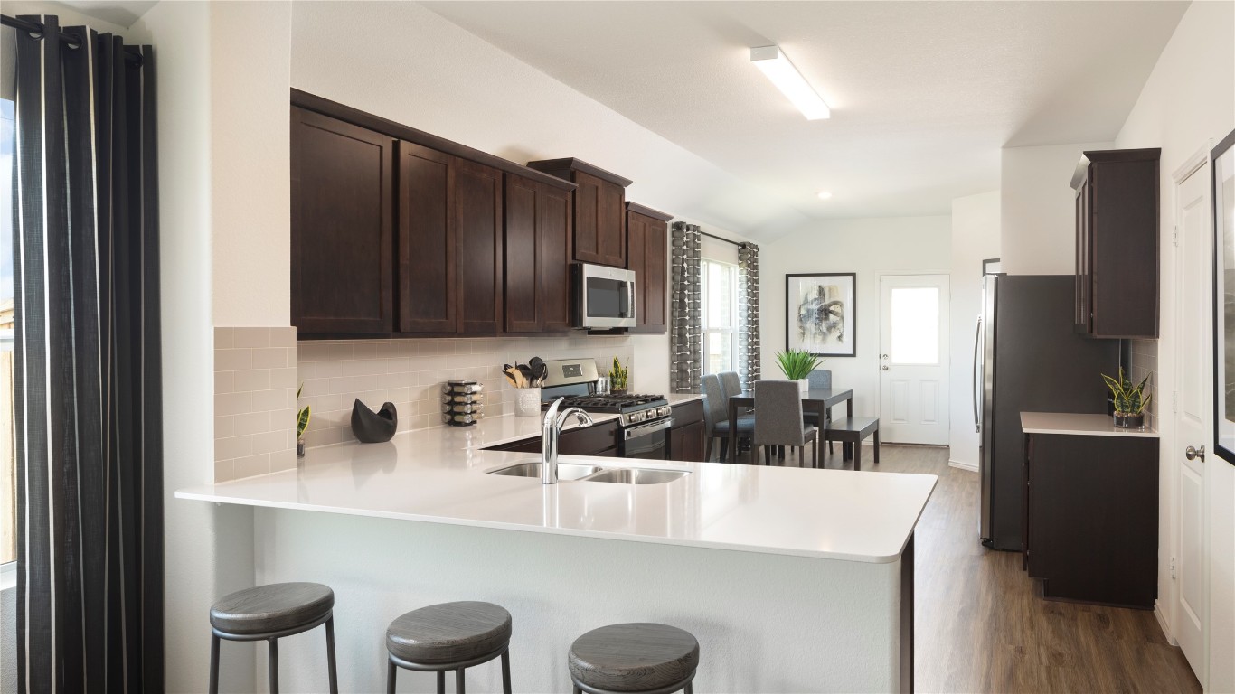 1409 Roaming Oak Bend Georgetown, TX 78628 - Photo 6 of 11 a kitchen with stainless steel appliances a sink and a refrigerator