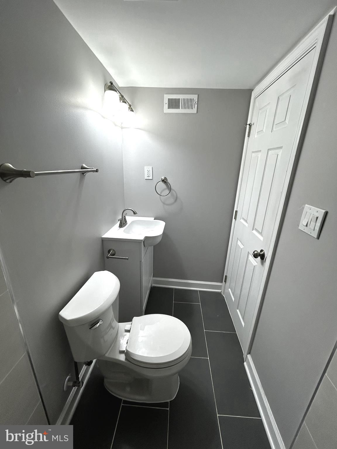 2815 East Chase Street Baltimore, MD 21213 - Photo 35 of 40 a white toilet sitting next to a bathroom sink and a shower