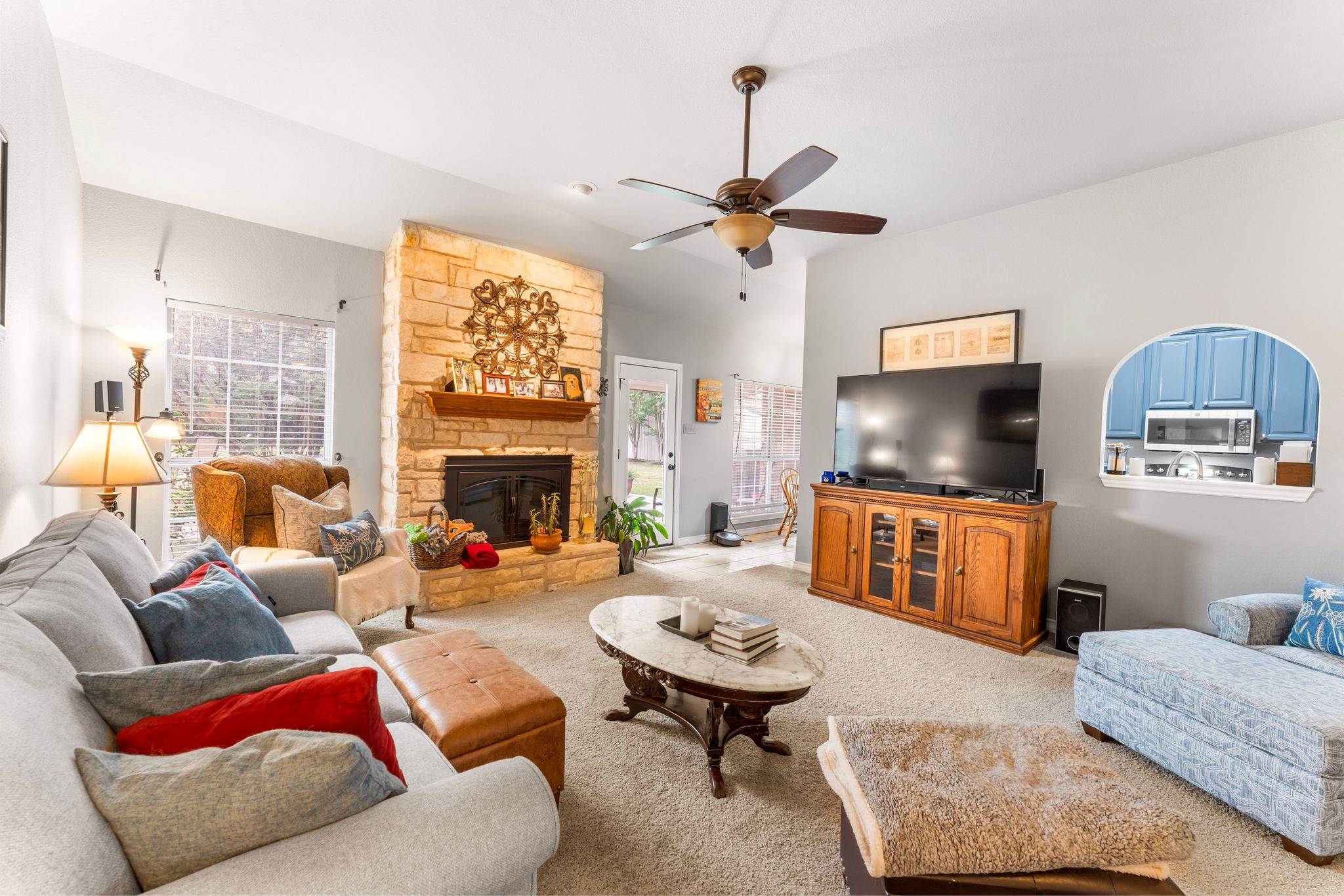 221 Breakaway Road Cedar Park, TX 78613 - Photo 22 of 39 Living room featuring carpet floors, plenty of natural light, a ceiling fan, and a stone fireplace