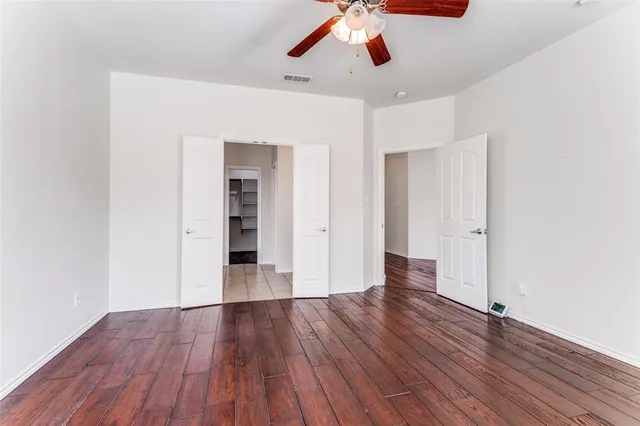 an empty room with wooden floor and ceiling fan