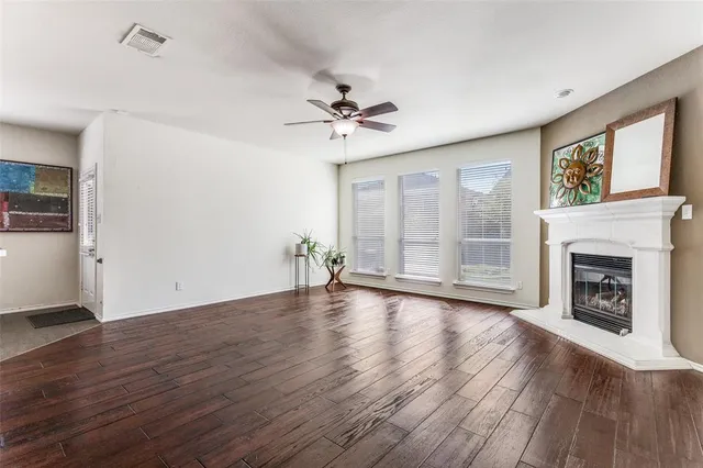 an empty room with wooden floor fireplace and windows
