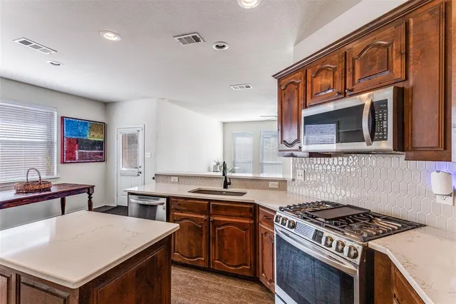 a kitchen with stainless steel appliances a stove a sink dishwasher and a refrigerator