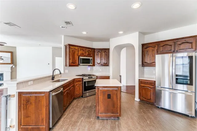 a kitchen with stainless steel appliances granite countertop a refrigerator a stove a sink and a microwave with wooden floor