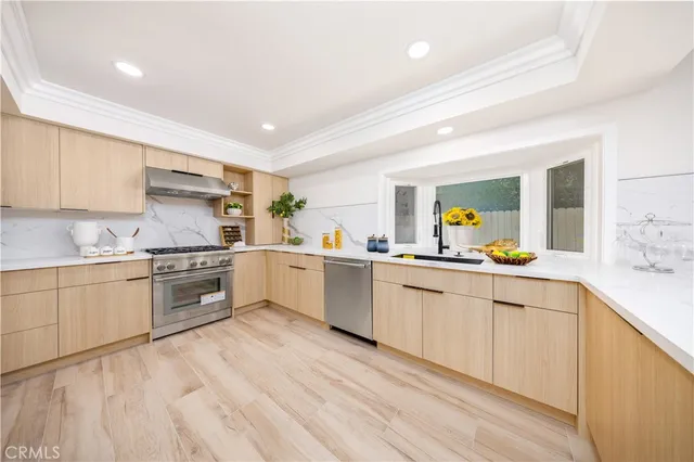 a kitchen with granite countertop white cabinets a sink dishwasher and a stove with wooden floor