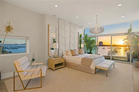 a spacious bedroom with a bed a couch and large window