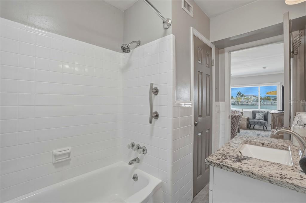 2605 Bay Boulevard Indian Rocks Beach, FL 33785 - Photo 24 of 82 a bathroom with a granite countertop sink a mirror and a bathtub