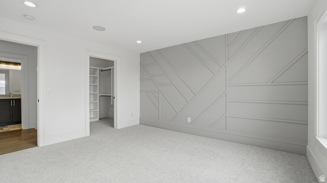 1682 North 1950 W Street, Unit 9 Provo, UT 84604 - Photo 63 of 84 Room featuring a statement wall with geometric paneling, light-toned carpeting, recessed ceiling lighting, and a walk-in closet with built-in shelving