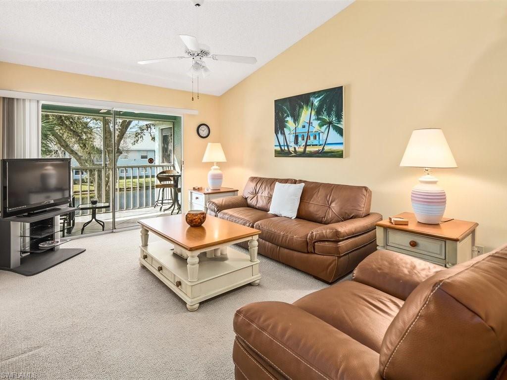 149 Wading Bird Circle, Unit I205 Naples, FL 34110 - Photo 1 of 27 a living room with furniture a flat screen tv and a large window
