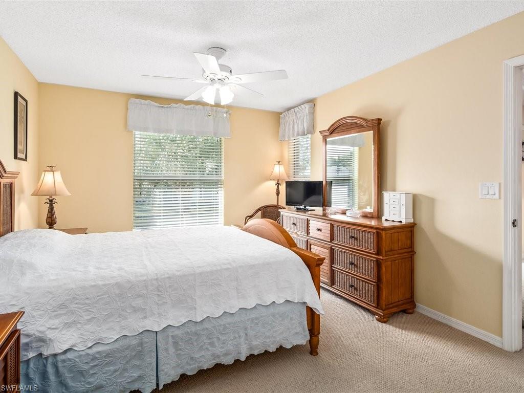 149 Wading Bird Circle, Unit I205 Naples, FL 34110 - Photo 12 of 27 a bedroom with a bed and a chandelier