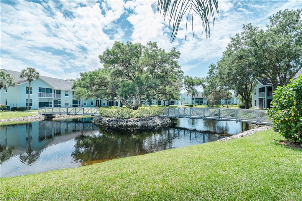 149 Wading Bird Circle, Unit I205 Naples, FL 34110 - Photo 22 of 27 a view of a lake with a yard and large trees