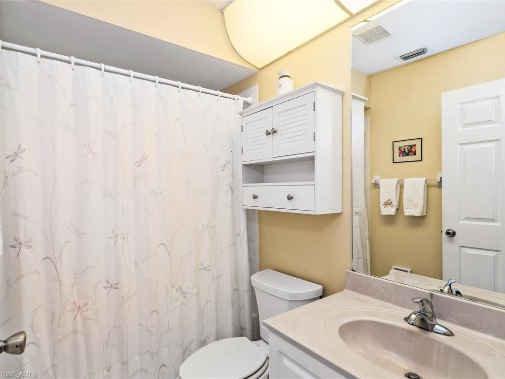 149 Wading Bird Circle, Unit I205 Naples, FL 34110 - Photo 3 of 27 a bathroom with a sink a toilet and shower curtain