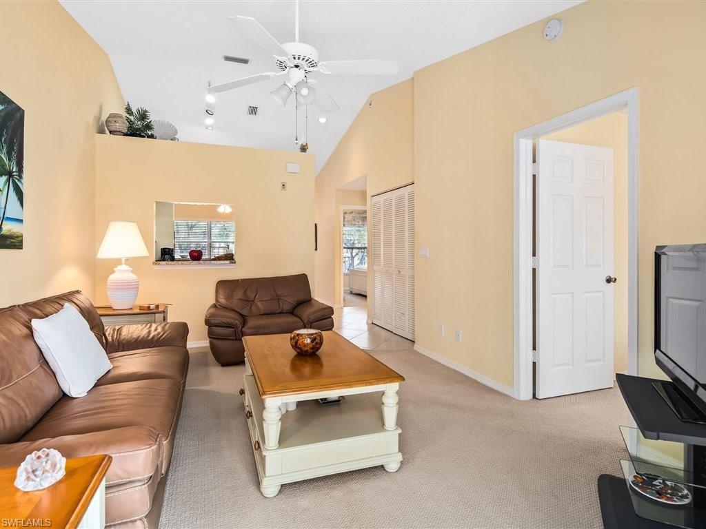 149 Wading Bird Circle, Unit I205 Naples, FL 34110 - Photo 4 of 27 a living room with furniture a flat screen tv and a fireplace
